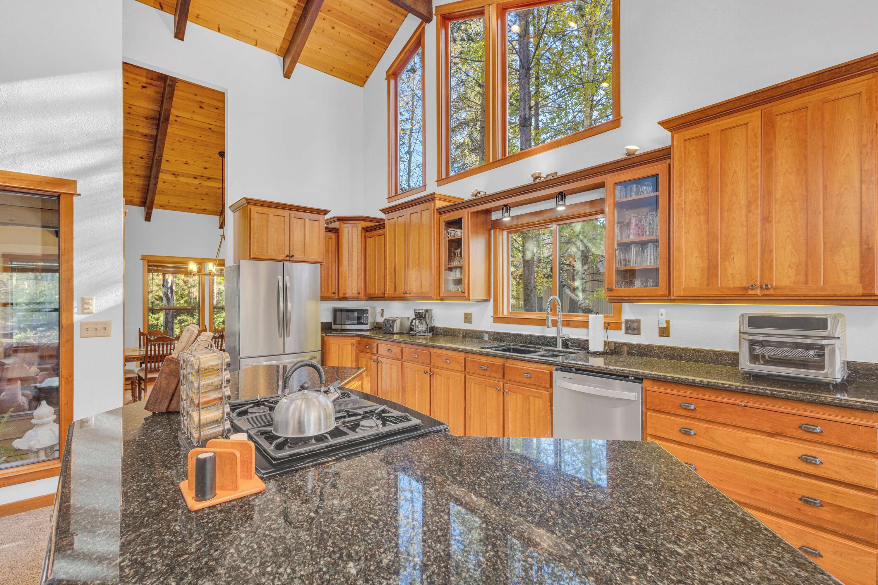 A spacious kitchen with wooden cabinets, a stainless steel refrigerator, a gas stove, and a built-in oven.