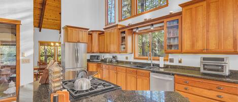 A spacious kitchen with wooden cabinets, a stainless steel refrigerator, a gas stove, and a built-in oven.