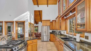 A spacious kitchen with wooden cabinets, a stainless steel refrigerator, and a gas stove. - Hot tub, large home, family friendly, ping pong, a premier Sunriver Retreat (Sunriver)