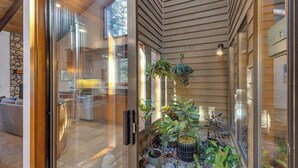 A modern interior with a glass door leading to a living area, wooden ceiling, and potted plants. - Hot tub, large home, family friendly, ping pong, a premier Sunriver Retreat (Sunriver)