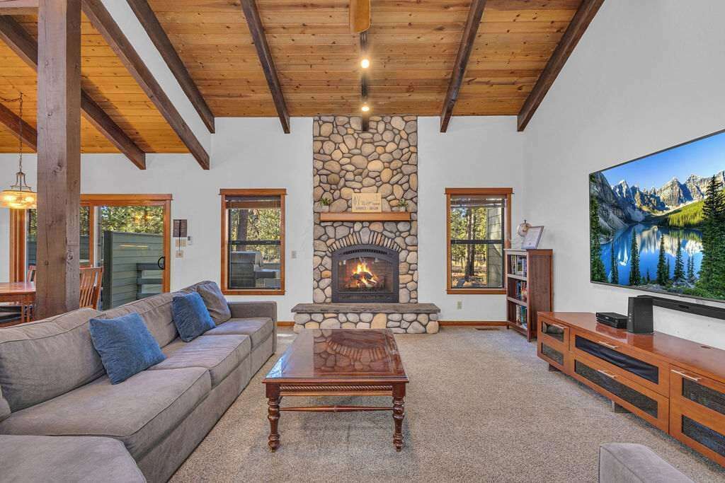 A cozy living room with a stone fireplace, a large flat-screen TV, and a comfortable sofa.