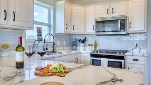 A modern kitchen with white cabinetry, a stainless steel microwave, and a marble countertop. - Welcome to The Palms @ Sneads Ferry, NC! (Sneads Ferry)