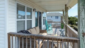 A covered porch with a wicker sofa, a turquoise chair, and a small table. - Welcome to The Palms @ Sneads Ferry, NC! (Sneads Ferry)