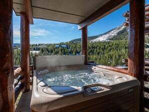 A hot tub with a control panel, surrounded by wooden beams, overlooking a snowy mountain and forested area. - Saddle Ridge F5 3 Bedroom Home (Gallatin Gateway)