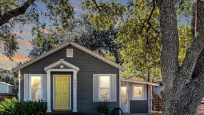 A single-story house with a front porch, a yellow door, and a small front yard.