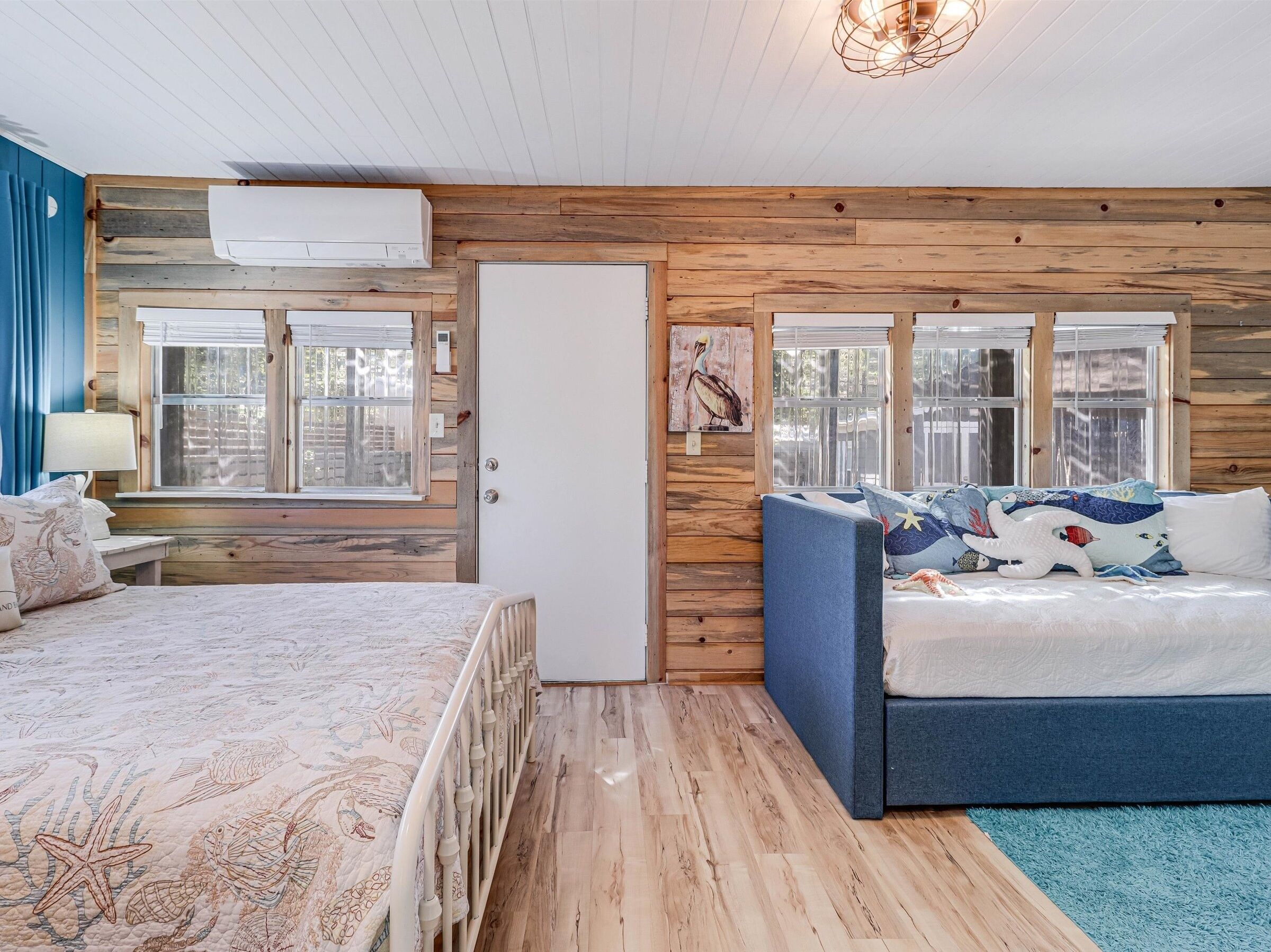 Een knus vertrek met een bed, een bank, houten wanden en een raam.