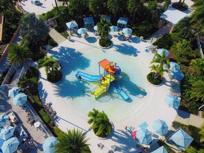 Ein Wasserpark mit einem zentralen Spielbereich, umgeben von Liegestühlen und Sonnenschirmen.