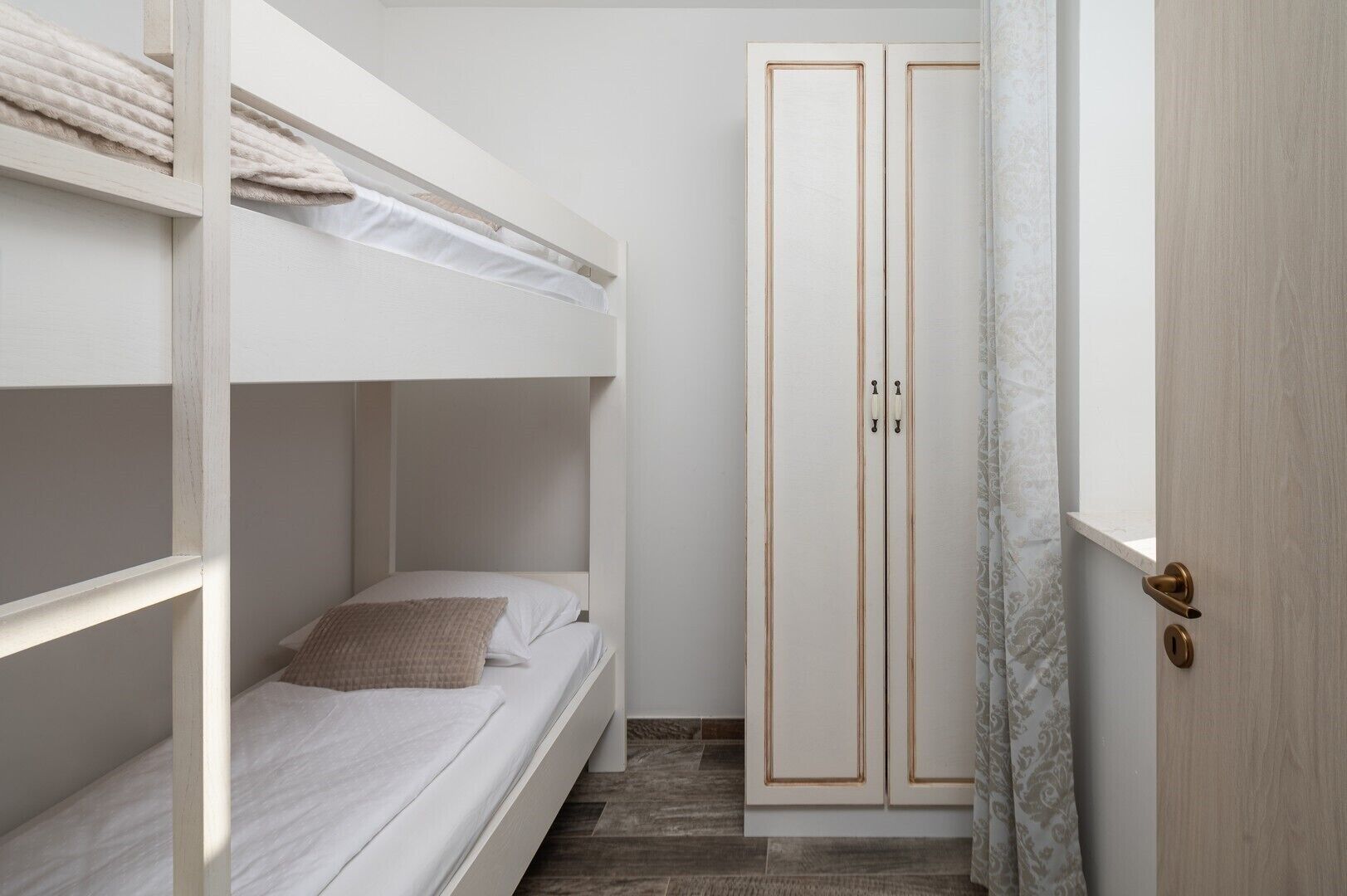 Ein Schlafraum mit Etagenbetten, einem Kleiderschrank und einer Tür.
