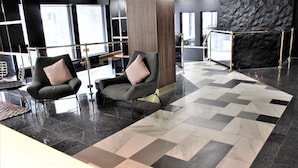 A lobby with two armchairs, a patterned floor, and a modern wall. - King Room in Hotel Downtown (Montréal)