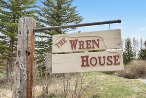 Welcome to The Wren House, nestled in a serene natural setting surrounded by trees and shrubs.