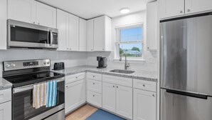 Une cuisine moderne avec des meubles blancs, des appareils en acier inoxydable et un tapis bleu sur le sol.