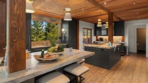 Une cuisine moderne dotée d’un grand îlot central, d’un plafond en bois et de luminaires suspendus.
