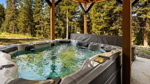 Ein Whirlpool mit einer hölzernen Pergola, umgeben von bewaldetem Gelände.