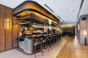 Enjoy a drink at the sleek bar, surrounded by a selection of beverages and comfortable seating.