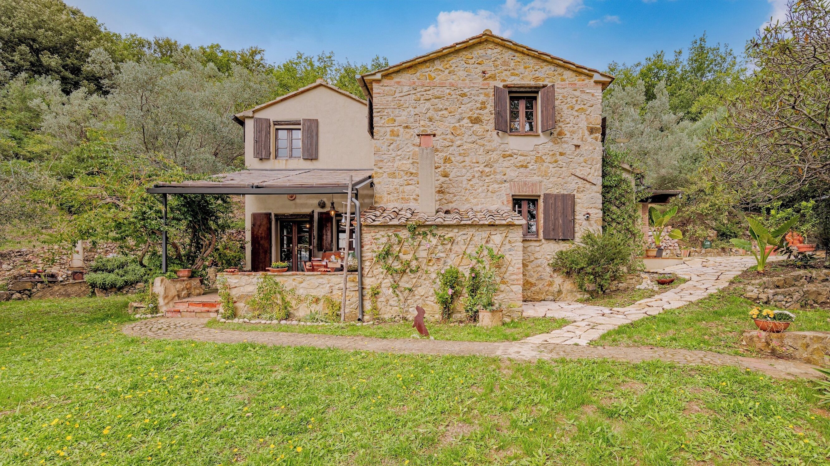 A stone house with a covered porch and a garden.