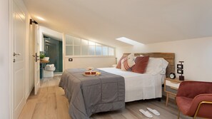 A modern bedroom with a large bed, bedside table, and a chair. - La Villanella 6, Emma Villas (Reggello)