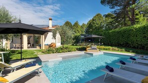 A swimming pool with lounge chairs, a covered patio, and a garden area with a pergola. - La Villanella 6, Emma Villas (Reggello)