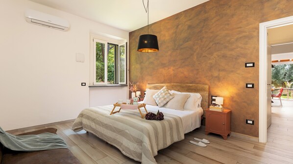 Une chambre à coucher avec un lit, des tables de chevet, une fenêtre et une vue sur l’extérieur.