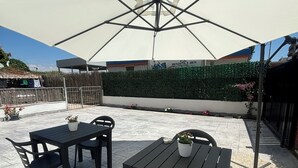 An outdoor patio with a large umbrella, black metal chairs, and a table. - At 100 mt from the sea and train station, rooms with all amenities (Nettuno)