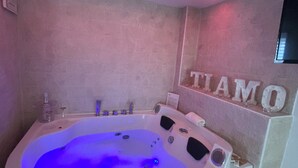 A spa room with a hot tub, a wall-mounted TV, and a sign that reads "TIAMO". - At 100 mt from the sea and train station, rooms with all amenities (Nettuno)