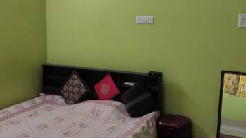 Un dormitorio con cama, mesita de noche, espejo y pared verde.