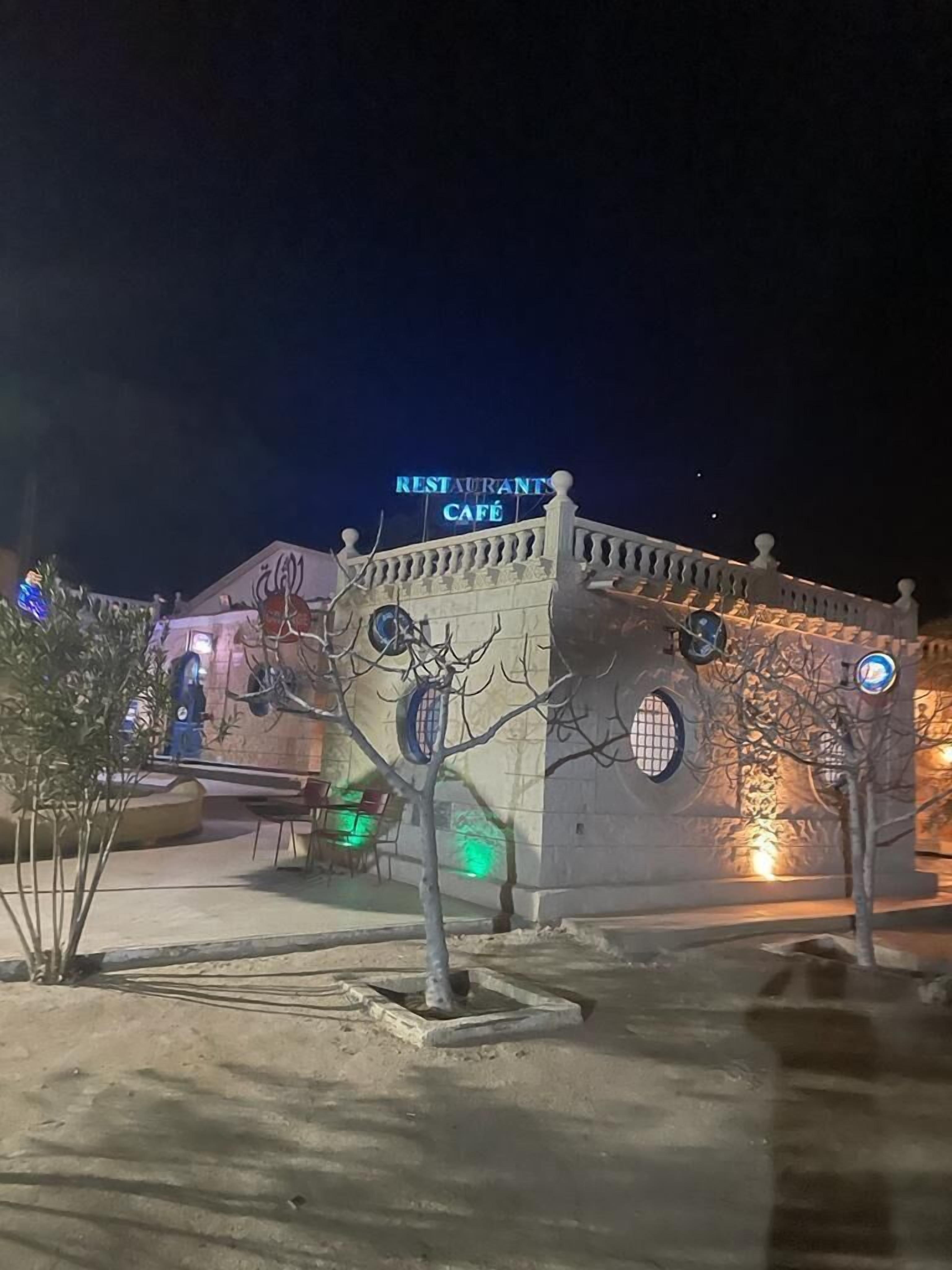 A building with a sign reading "RESTAURANTS CAFÉ" at night.