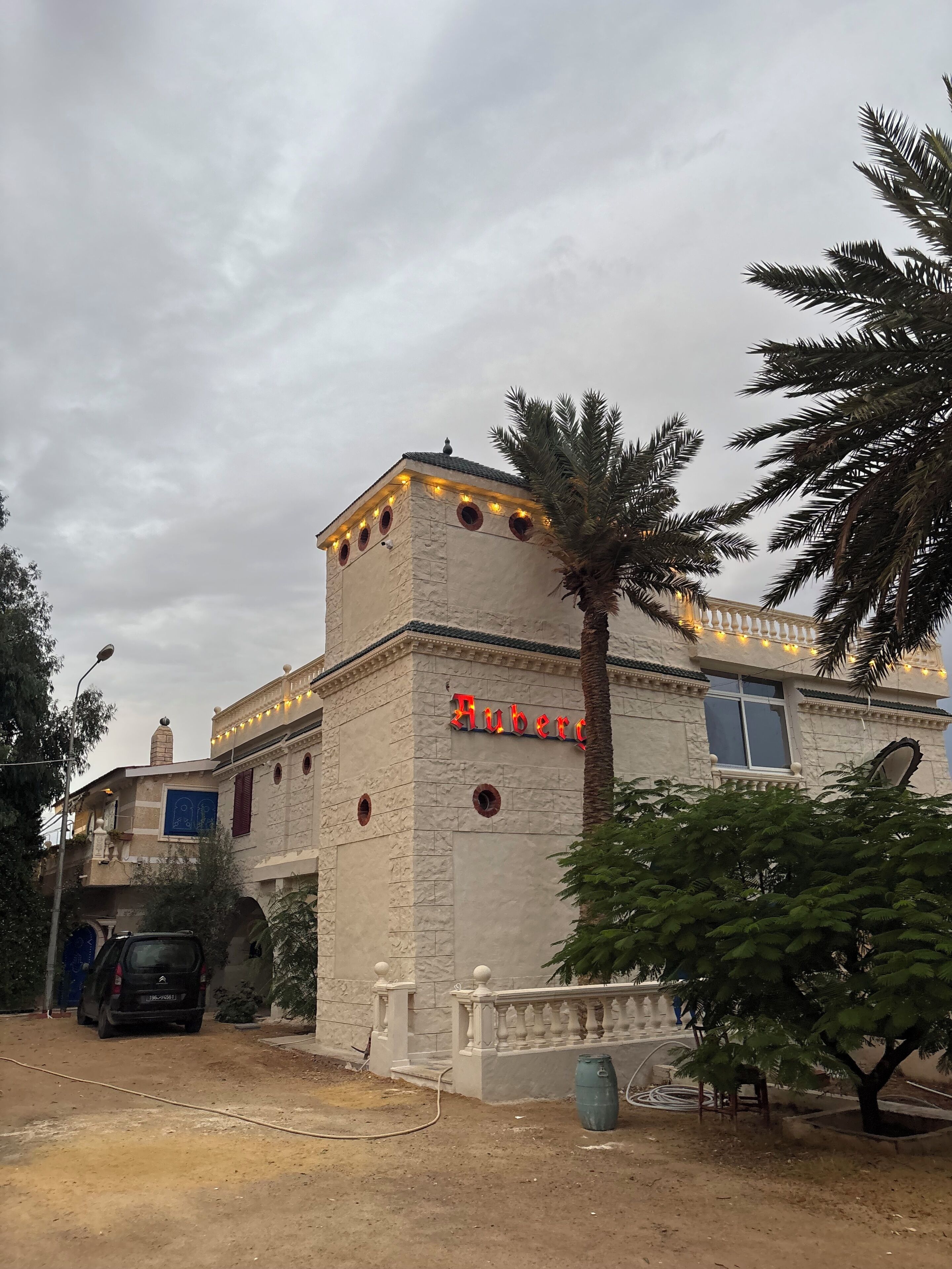 Un edificio con fachada de piedra, un letrero que dice "Huberg" y una palmera en primer plano.