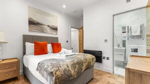 A modern bedroom with a large bed, a bedside table, a mirror, and a wardrobe. - Mill Conversion Flat Mins from Printworks - Pass the Keys (Salford)