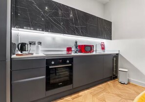Una cocina moderna con un salpicadero de mármol blanco y negro, un horno Bosch y un microondas rojo.