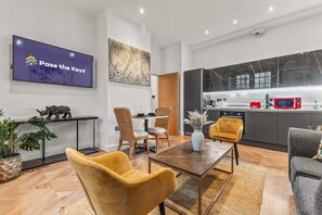 Una sala de estar moderna con comedor, cocina y un televisor con 'Pass the Keys' en la pantalla.