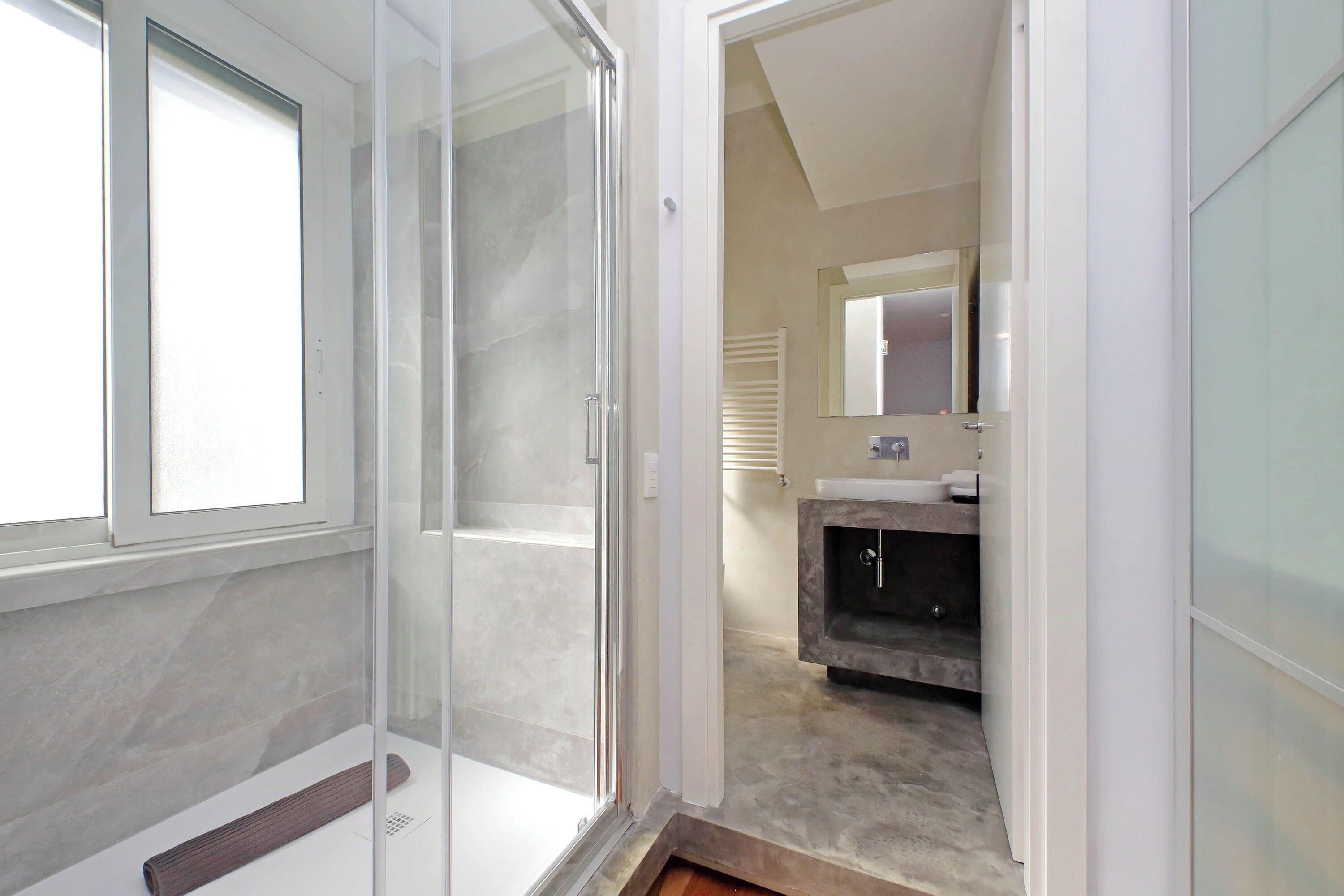 Un baño moderno con cabina de ducha de vidrio, tocador con lavabo y espejo sobre el tocador.