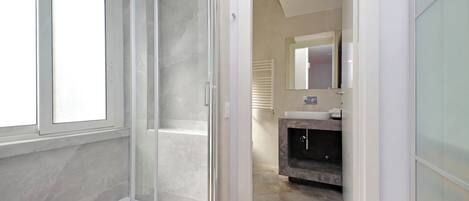 Un baño moderno con cabina de ducha de vidrio, tocador con lavabo y espejo sobre el tocador.