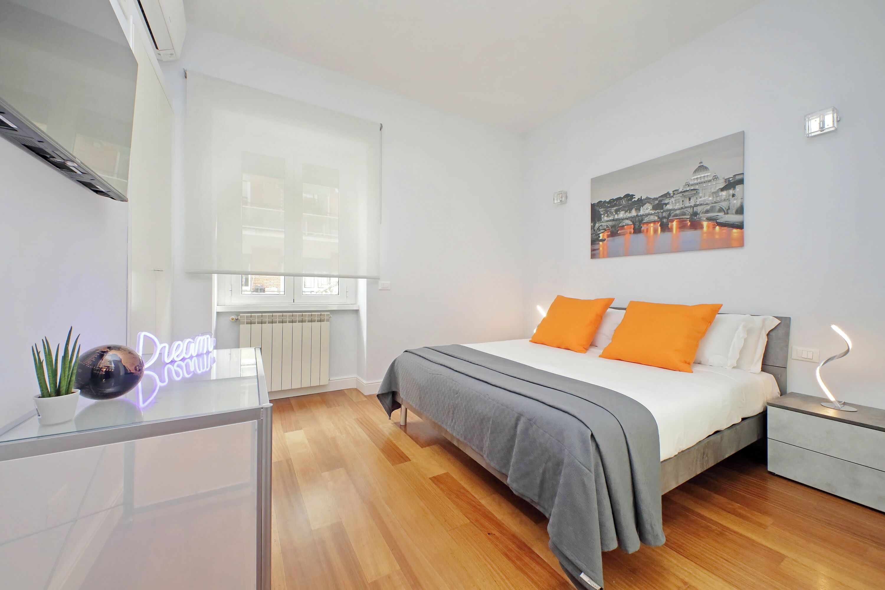 Une chambre à coucher moderne avec un lit, des tables de chevet, un radiateur et une fenêtre.