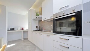 Eine moderne Küche mit weißen Schränken, einem eingebauten Backofen und einer Mikrowelle.