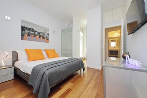 Ein modernes Schlafzimmer mit einem Bett, einem Nachttisch, einem Beistelltisch, einem Spiegel und einem am Wand montierten Fernseher.