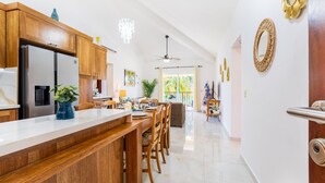 Una cocina moderna con armarios de madera, un refrigerador de acero inoxidable y una barra con taburetes.