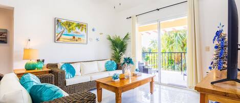 A spacious living room with a wooden coffee table, wicker sofa, and a ceiling fan.