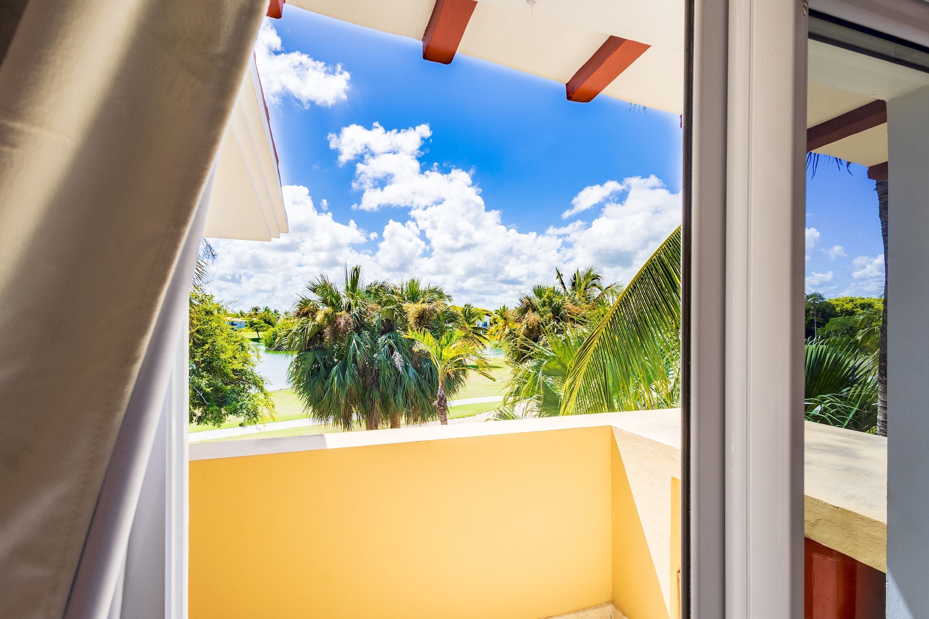 Un balcón con vista a palmeras y cielo despejado.