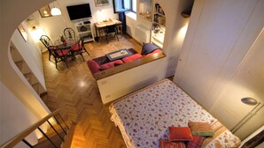 En kompakt opholdsstue med sofa, spiseplads med stole, et lille bord og et fjernsyn.