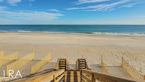 A beach with a wooden boardwalk leading to a sandy area, a clear blue sky, and the ocean in the background. - Beachy McBeach House: Bold, Bright & Beachy (Surf City)