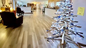 Una habitación amplia con piso de madera, un mostrador de recepción y un árbol de Navidad original hecho con ramas y luces.