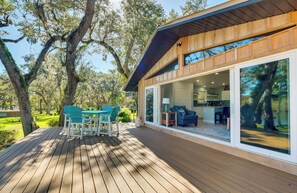 A wooden deck with outdoor seating, large windows, and a view of trees. - Waterfront Home w/ Boat Dock & Slip in Old Town! (Old Town)