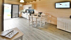 A modern kitchen with white cabinets and a dining area with a wooden table and chairs. - Holiday homes near the sea, sauna, whirlpool (Sianozety)