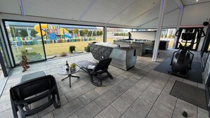 A modern outdoor area with a seating arrangement, exercise equipment, and a view of a playground. - Holiday homes close to the beach, air conditioning (Sianozety)