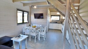 A dining area with a table set for four, a TV mounted on the wall, and a kitchen area with a sink and cabinets. - Holiday homes close to the beach, air conditioning (Sianozety)