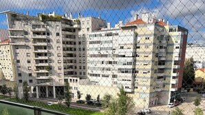 Ein Balkon mit Blick auf einen Wohnkomplex, eine Rasenfläche und eine Straße mit parkenden Autos.
