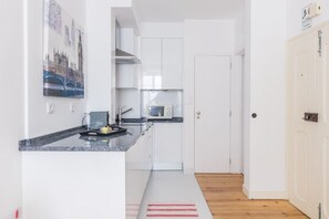 A modern kitchen with white cabinets, a microwave, and a coffee maker on the countertop.