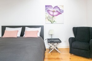 A bedroom with a bed, a nightstand, a lamp, and a chair. - Cozy duplex in the heart of Lisbon's Bairro Alto (Lisboa)