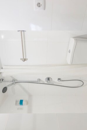 A modern bathroom with a glass shower enclosure, a handheld showerhead, and a built-in soap dispenser.