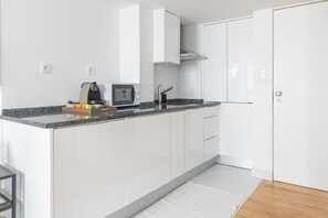 A modern kitchen with white cabinets, a granite countertop, and a built-in microwave. - Cozy duplex in the heart of Lisbon's Bairro Alto (Lisboa)